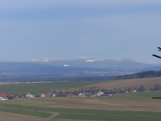 Potštejn - pohled ze silnice od kamenolomu do Potštejna na zasněžený hřeben Orlických hor. V popředí je část obce Merklovice