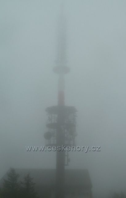 Vysoká věž televizního dokrývače Valašské Meziříčí na vrcholu Radhoště nesměle proráží mlhou