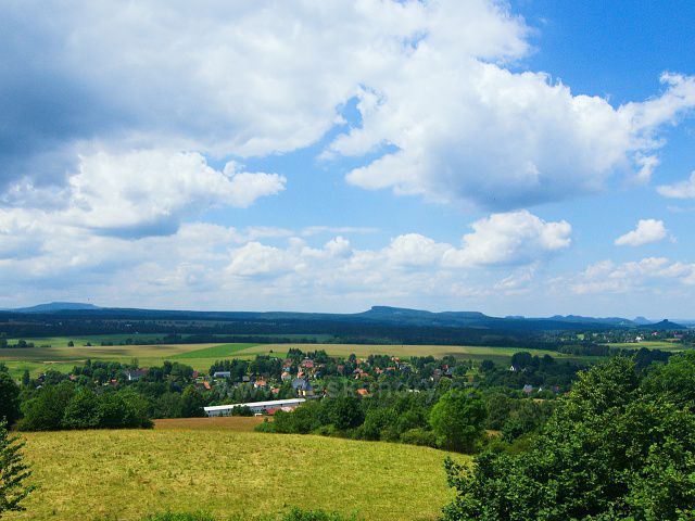 Výhled z rozhledny Růženka na Pastevním vrchu. U levé strany na obzoru Děčínský Sněžník, vravo od středu Velký a Malý Zschirnstein, u levého okraje výrazné vrcholy  Lilienstein a Zirkelstein.